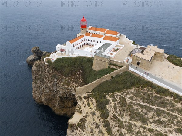 A red lighthouse on a cliff above the ocean, surrounded by white buildings and a picturesque landscape, aerial view, lighthouse, Cabo de São Vicente, Cape St Vincent, Cape St Vincent, Sagres, Portugal, Europe