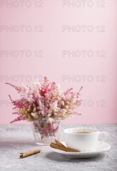 Pink and red astilbe flowers in glass and a cup of coffee on a gray and pink background. Morninig, spring, fashion composition. side view, close up, selective focus