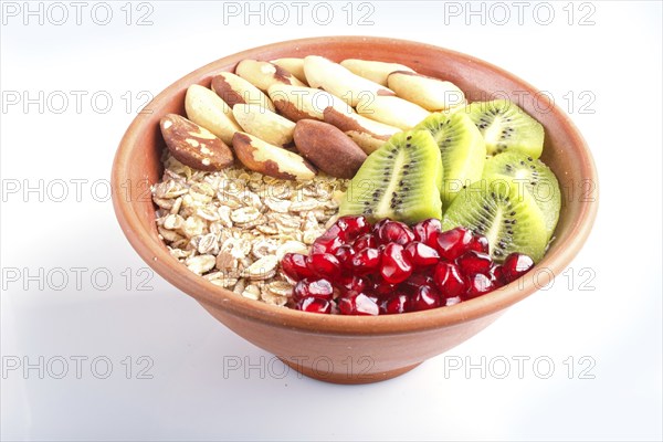 A plate with muesli, kiwi, pomegranate, Brazil nuts isolated on white background. close up