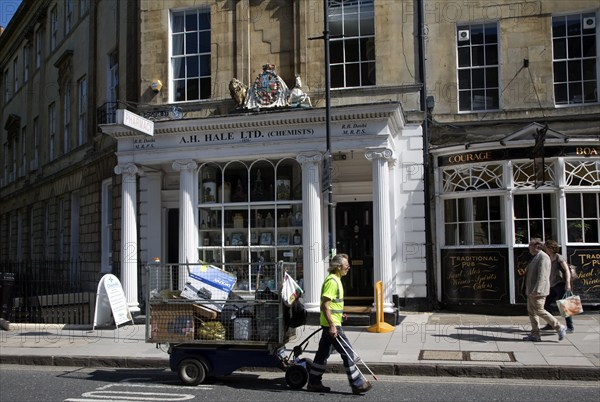 Street cleaner pulling a rubbish collection cart in Argyle Street, Bath, Somerset, England, United Kingdom, Europe