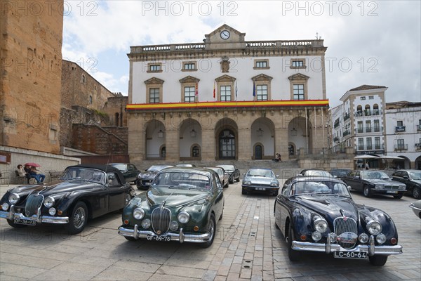 A square with a row of classic cars in front of a historic building, town hall, Ayuntamiento, vintage car, Plaza Mayor, Cáceres, Caceres, Extremadura, Spain, Europe