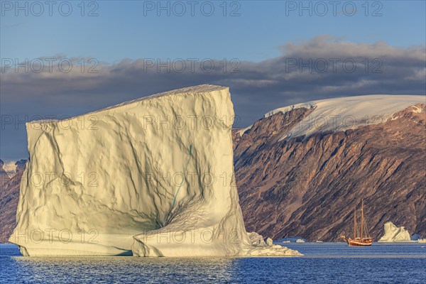 Sailing boat, ship in fjord in front of large icebergs and mountains, evening light, Scoresby Sound, East Greenland, Greenland, North America