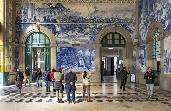 Visitors admire the azulejo tile mural at São Bento Railway Station, Porto, Portugal, Europe