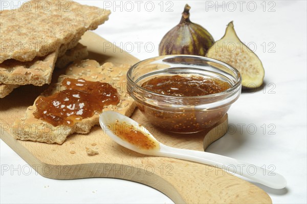 Fig jam in small bowls and on crispbread, Ficus carica