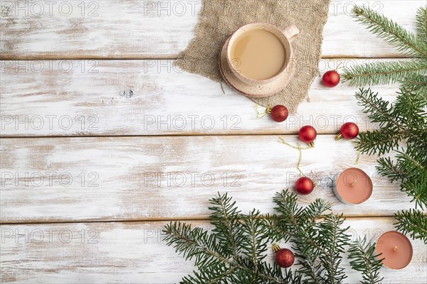 Christmas or New Year composition. Decorations, red balls, fir and spruce branches, cup of coffee, candles on a white wooden background. Top view, copy space, flat lay