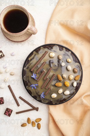 Homemade chocolate brownie cake with caramel cream and almonds with cup of coffee on a white concrete background and orange textile. top view. flat lay, close up