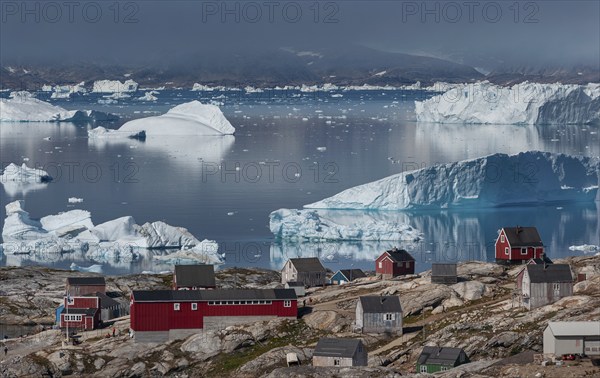 Large icebergs floating in fjord behind Inuit settlement Tiniteqilaaq, Sermilik Fjord, East Greenland, Greenland, North America