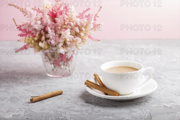 Pink and red astilbe flowers in glass and a cup of coffee on a gray and pink background. Morninig, spring, fashion composition. side view, close up, selective focus