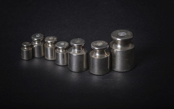 A set of small metal weights on a gray background