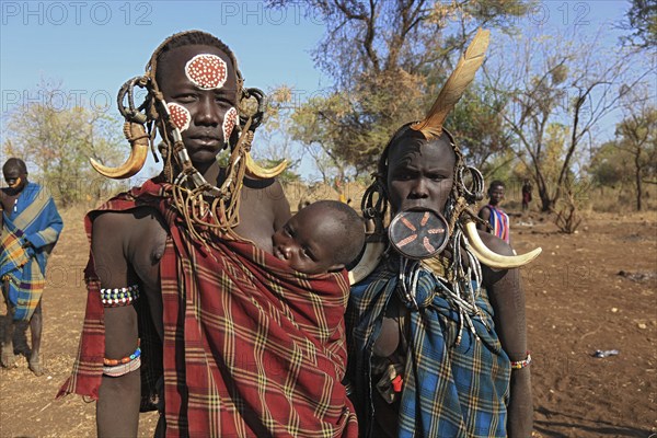 South Ethiopia, in Maco National Park, Mursi tribe, Mursi woman with baby, painted skin and headdress, young plate lip woman, plate in lip, body jewellery, Ethiopia, Africa