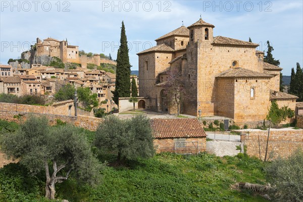 A historic town with medieval buildings and a stone church surrounded by cypresses and trees under a blue sky, collegiate church on the hill, Colegiata de Santa María la Mayor, parish church of San Miguel, Alquézar, Alquezar, Huesca, Aragón, Aragon, Pyrenees, Spain, Europe