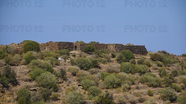 Ancient ruined wall in an arid landscape under a blue sky with low vegetation, Palaiokastro, Ancient fortress, 3rd and 4th century BC, above Mandraki, Nisyros, Dodecanese, Greek Islands, Greece, Europe