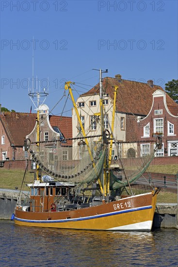 Crab cutter in the harbour in front of historic buildings, blue sky, Greetsiel, North Sea, Lower Saxony, Germany, Europe