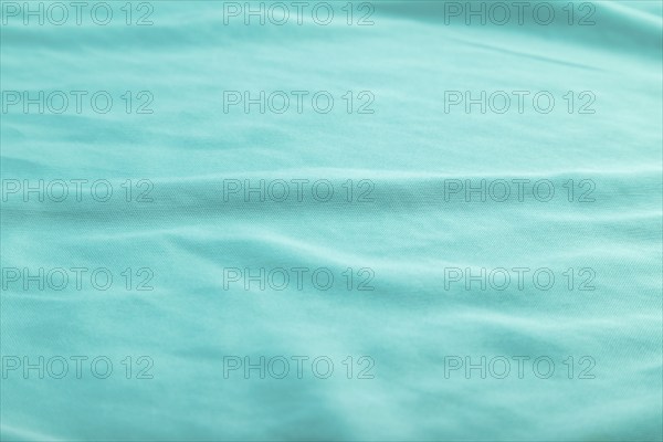 Fragment of smooth silk blue tissue. Side view, natural textile background and texture