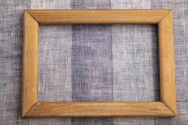 Wooden frame on smooth brown and violet linen tissue. Top view, flat lay, natural textile background and texture