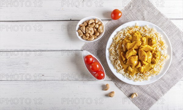 Rice with chicken curry sauce with cashew on white wooden background. top view, copy space