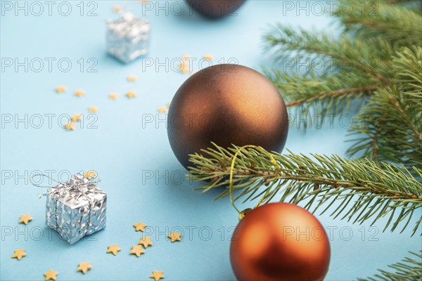 Christmas or New Year composition. Decorations, bronze balls, fir and spruce branches, on a blue paper background. Side view, close up, selective focus