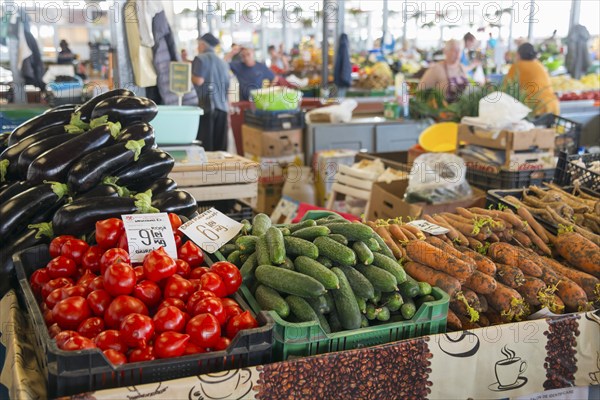 Colourful display of vegetables at a market stall with price tags and background activity, market hall, Fagaras, Fagara?, Fogarasch, Fugreschmarkt, Brasov, Transylvania, Romania, Europe