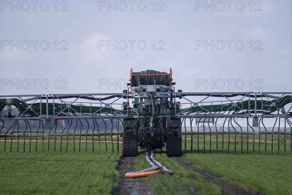 Tractor with boom for spreading liquid manure, on a field, fertilisation