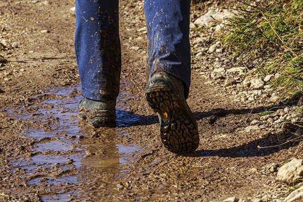 A person in hiking boots on a muddy path outdoors