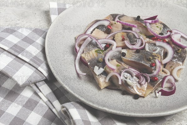 Salted herring, with spices and red onion, sliced fillet, on a plate, top view