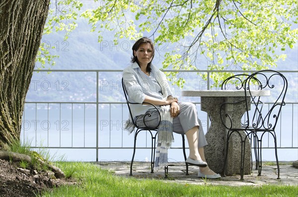 Elegant Business Woman Titting in a Patio with a Tree in Ascona, Switzerland, Europe