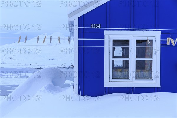 Typical Greenlandic house in deep snow in front of mountains, winter, Tasiilaq, East Greenland, Greenland, North America