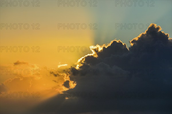 Golden sunbeams break through clouds at sunrise and create the Tyndall effect