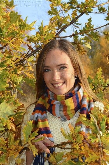 Portrait of young beautiful smiling woman, 30 years old, outdoors in forest with autumn colors in Ystad, Skåne County, Sweden, Scandinavia, Europe