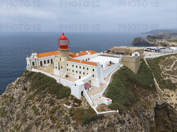 A red lighthouse on a rocky cliff, surrounded by white buildings, overlooking the ocean, aerial view, lighthouse, Cabo de São Vicente, Cape St Vincent, Cape St Vincent, Sagres, Portugal, Europe