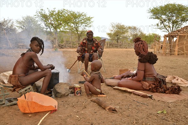 Chief Hikuminue Kapika, tribal leader of the Namibian Himba people, sitting with his family at a fire in his kraal, Omuramba, Kaokoland, Kunene, Namibia, Africa