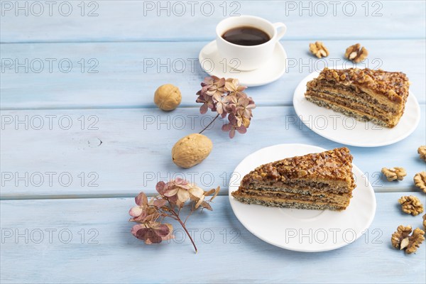 Walnut and hazelnut cake with caramel cream, cup of coffee on blue wooden background. side view, copy space