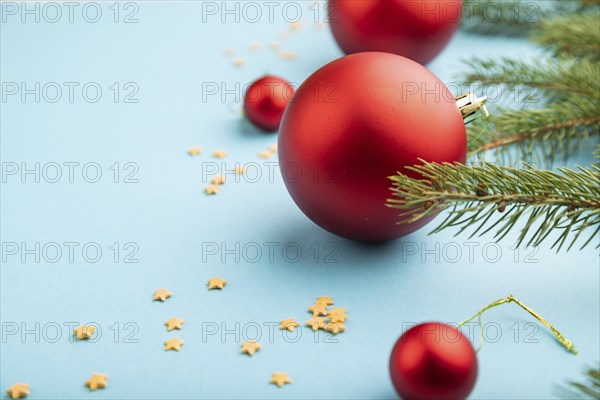 Christmas or New Year composition. Decorations, red balls, fir and spruce branches, on a blue paper background. Side view, copy space