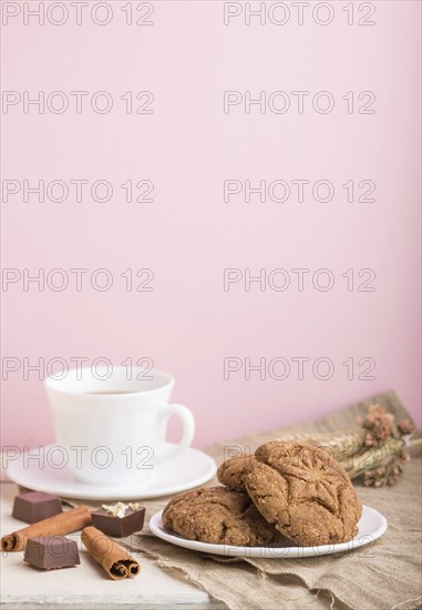 Homemade oatmeal cookies with a cup of cocoa on a linen textile and pink pastel background. side view, close up, selective focus, copy space