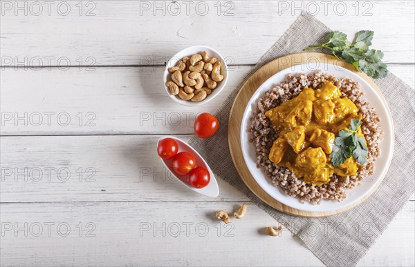 Buckwheat with chicken curry sauce with cashew on white wooden background. top view, copy space