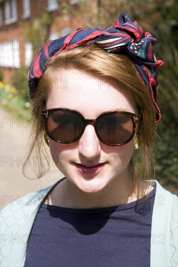 Model released head and shoulders portrait of teenage girl wearing sunglasses and head scarf outdoors, UK