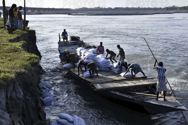 Public Works Department (PWD) of Assam labourer throwing sand bag from boat in the banks of Beki River to reduce soil erosion in Barpeta, Assam in India on Tuesday, November 13, 2018. The soil erosion of Beki river has become a major problem of flowing two districts Barpeta and Baksa of Assam