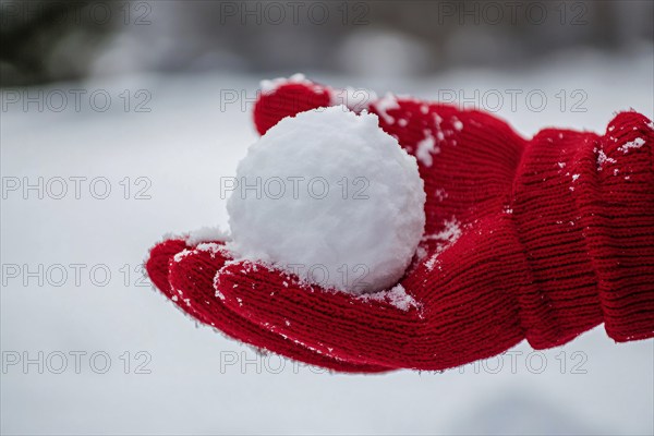 Hand in red knitted glove holding snowball. Generative Ai, AI generated