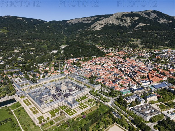 Large historic monastery and surrounding town in a green and mountainous landscape, taken from the air, aerial view, Real Sitio de San Lorenzo de El Escorial, Royal Seat of St Lawrence of El Escorial, palace and monastery complex, San Lorenzo de El Escorial, Madrid, Spain, UNESCO World Heritage Site, Europe