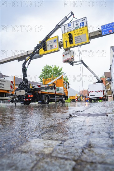 Two cranes working on display boards on wet ground in the rain, Hermann Hesse railway construction site, Calw, Black Forest, Germany, Europe