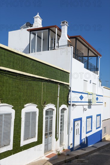 Modern house with green tiles and white facade. Balconies and windows, blue sky in the background, house with azulejos, Fuseta, Fuzeta, Faro, Algarve, Portugal, Europe