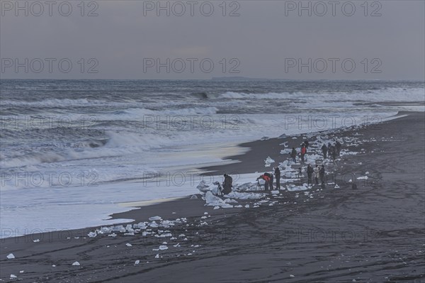 Tourists photographing ice floes on the beach, waves, sea, clouds, winter, Diamond Beach, Breidamerkursandur, Jökulsarlon, Iceland, Europe