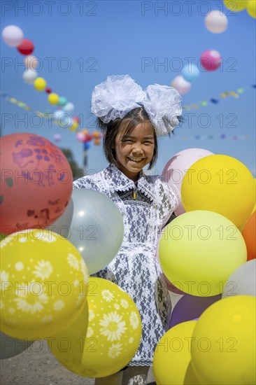 Happy schoolgirl with colourful balloons on the first day of school, Issyk-Kul region, Kyrgyzstan, Asia