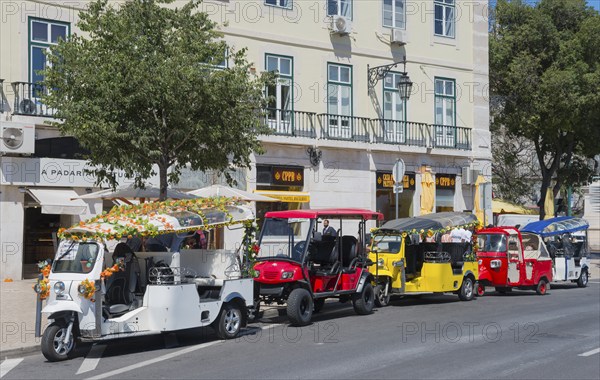 Row of colourful tuk-tuks on a city street in front of a building in sunny weather, Lisbon, Lisboa, Portugal, Europe