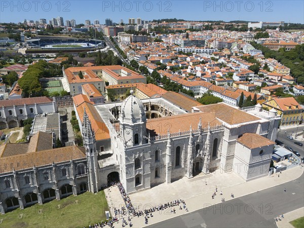 Aerial view of a cathedral with dome and towers, in the middle of a city with orange-coloured roofs and modern buildings in the background, aerial view, Hieronymus Monastery, Mosteiro dos Jerónimos, Hieronymite Monastery, World Heritage Site, Monastery Church of Santa Maria, Belém, Belem, Bethlehem, Lisbon, Lisboa, Portugal, Europe