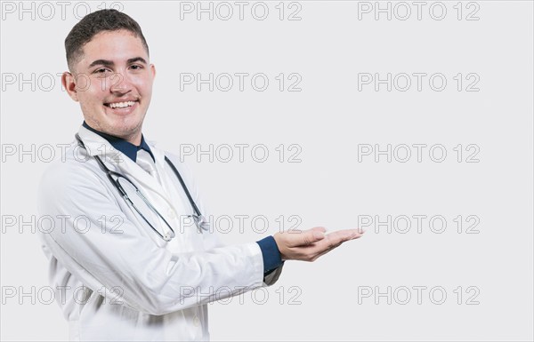 Happy doctor presenting something with his palms. Handsome doctor showing an advertisement with his palms