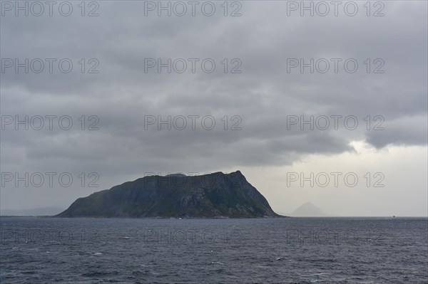 An island in the sea under a cloudy, gloomy sky, Alesund, Fylke, Norway, Europe