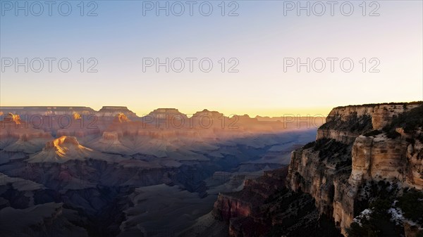 Sunrise over grand canyon in vibrant colors casting light on overhanging rock formations, AI generated