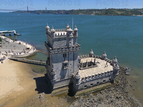 A historic tower on a rocky shore with blue water and sky in the background, aerial view, Torre de Belém, World Heritage Site, Belem, Bethlehem, Lisbon, Lisboa, River Tagus, Portugal, Europe