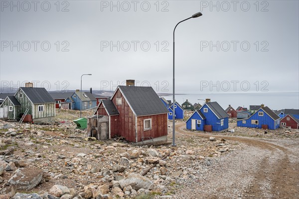 Colourful houses and gravel road with street lamps on a fjord, remote Arctic Inuit settlement Ittoqqortoormiit, Scoresbysund or Scoresby Sund or Greenlandic Kangertittivaq, East Greenland, Greenland, North America